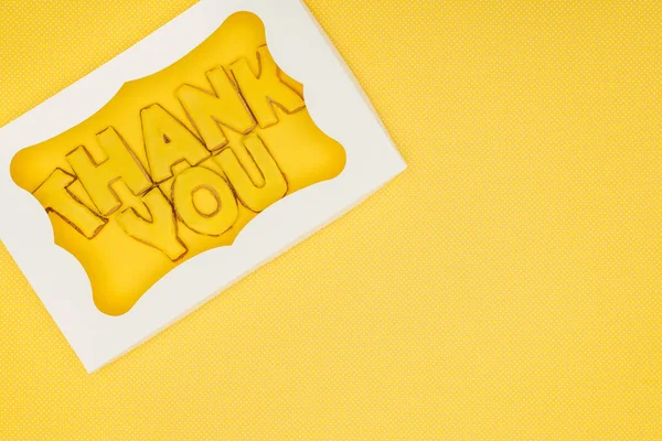 Square-shaped cake in box with thank you lettering isolated on yellow background — Stock Photo