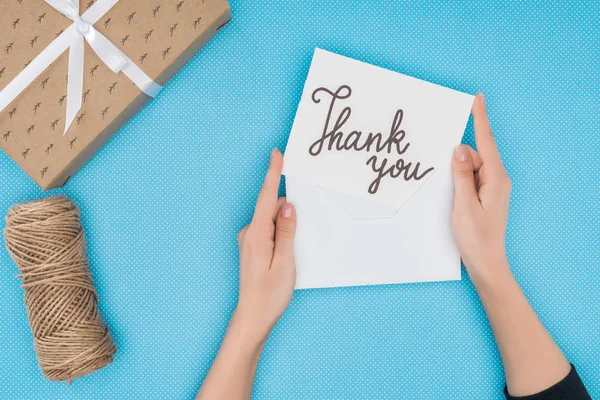 Persona recortada sosteniendo papel con letras de agradecimiento aislado sobre fondo azul - foto de stock