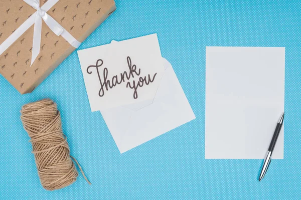 Carte postale blanche avec lettrage de remerciements et feuille blanche isolée sur fond bleu — Photo de stock