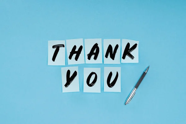 Thank you wording on sticky notes and pen isolated on blue background — Stock Photo