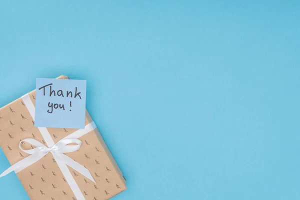Sticky note with thank you lettering on gift box isolated on blue background — Stock Photo