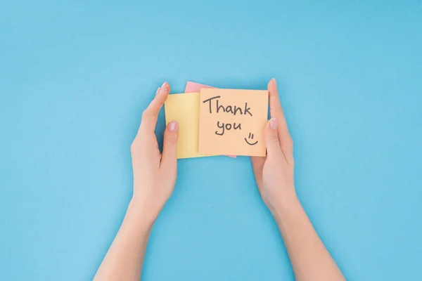 Cropped person holding colorful sticky notes with thank you lettering isolated on blue background — Stock Photo