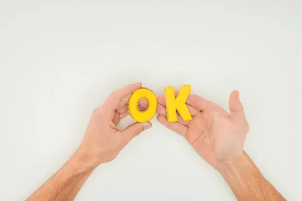 Cropped person holding ok word in yellow cookies solated on white background — Stock Photo