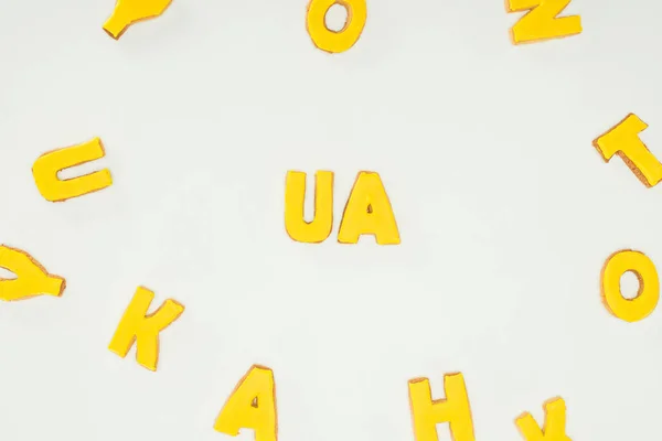 Sinal ua feito de biscoitos amarelos e letras espalhadas alfabeto isolado no fundo branco — Fotografia de Stock