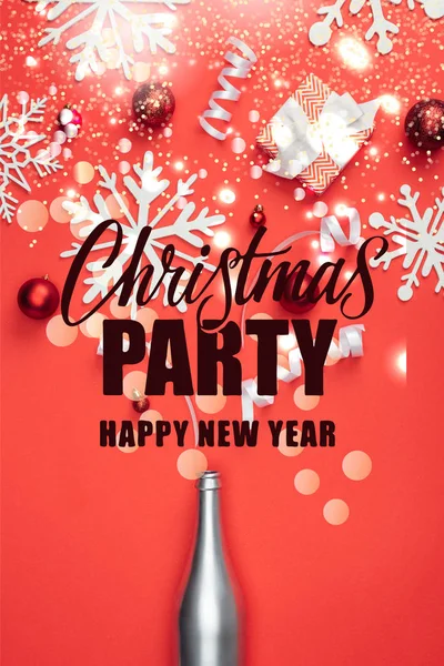 Draufsicht auf Geschenk, Champagnerflasche, rotes Weihnachtsspielzeug, weiße Bänder und dekorative Schneeflocken vereinzelt auf rotem Grund mit dem Schriftzug 