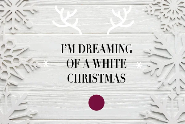 Flat lay com flocos de neve decorativos em fundo de madeira branco com inspiração 