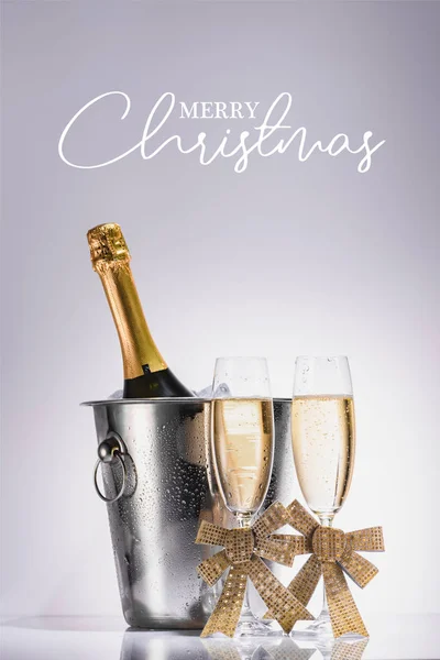 Bottiglia di champagne in secchio e bicchieri di champagne su sfondo grigio con scritta 