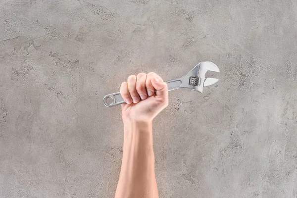 Tiro cortado de homem segurando chave de tubo na superfície de concreto — Fotografia de Stock