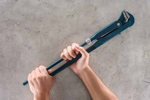 Cropped shot of man holding plumber wrench on concrete surface — Stock Photo