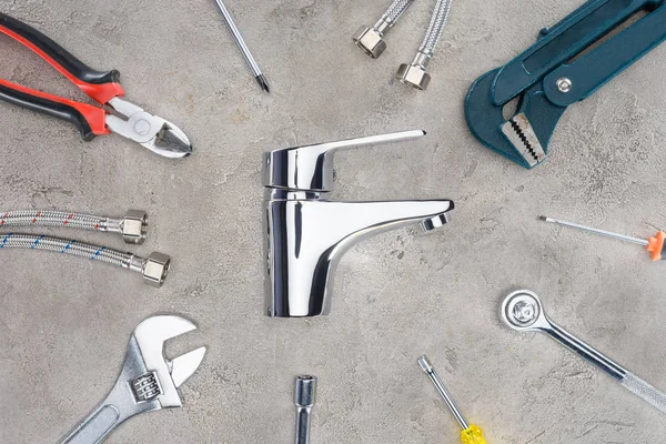 Top view of water mixer surrounded with various tools on concrete surface — Stock Photo