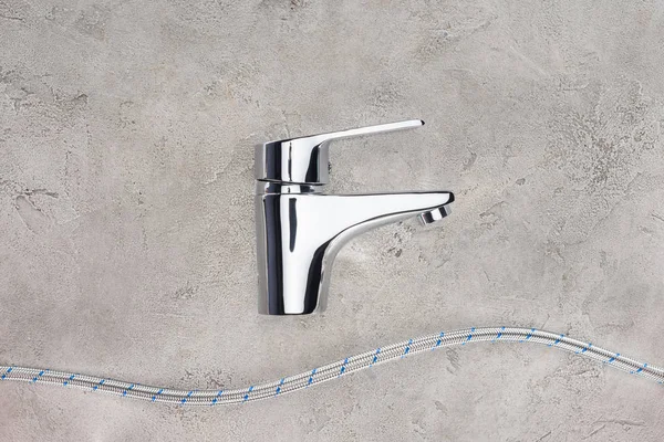 Draufsicht auf Wassermischer mit flexiblem Rohr auf Betonoberfläche — Stockfoto