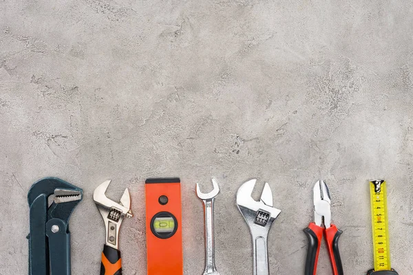 Flat lay with row of various tools on concrete surface — Stock Photo