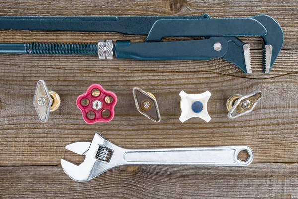 Top view of plumber wrenches and various plumbing valves on rustic wooden tabletop — Stock Photo