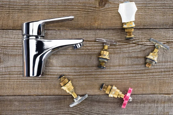 Top view of mixer and various plumbing valves on rustic wooden tabletop — Stock Photo