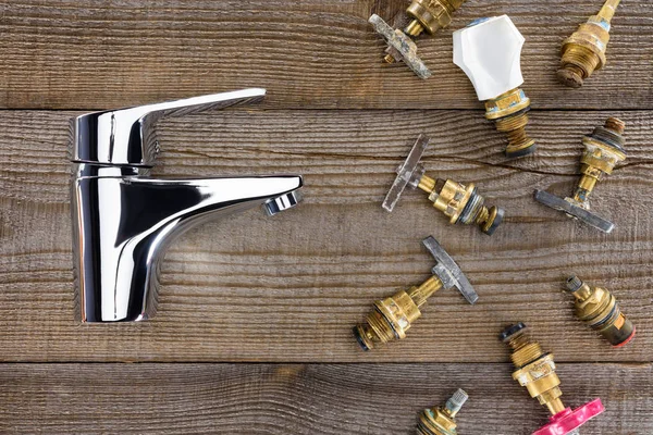 Top view of water mixer and various plumbing valves on rustic wooden tabletop — Stock Photo