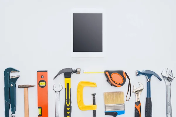 Top view of tablet with various tools lying on white — Stock Photo