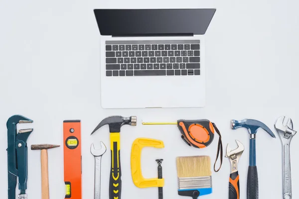 Draufsicht auf Laptop mit verschiedenen Instrumenten auf weißem Grund — Stockfoto