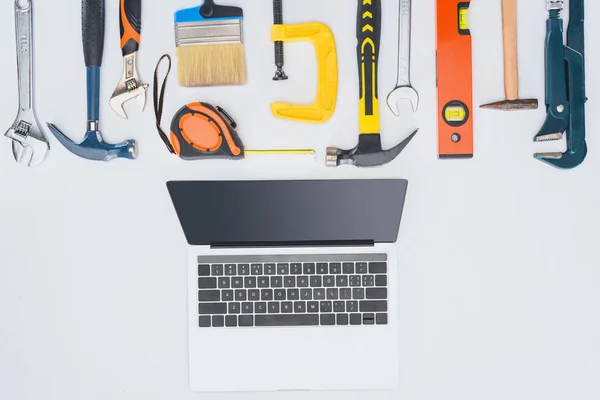 Top view of laptop with different tools lying on white — Stock Photo