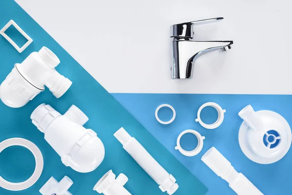 Vista dall'alto di pezzi idraulici in plastica e miscelatore d'acqua isolato su bianco — Foto stock
