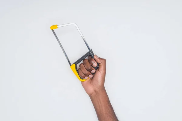 Обрізаний знімок афроамериканського чоловіка, що тримає ножівку ізольовано на білому — стокове фото