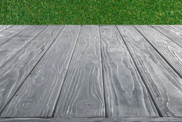 Oberfläche aus grauen Holzplanken auf grünem Grashintergrund — Stockfoto