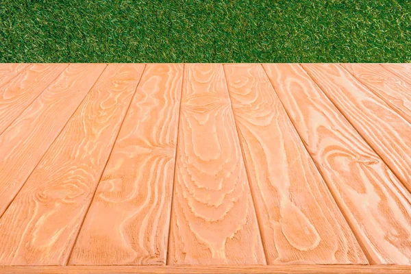 Surface of orange wooden planks on green grass background — Stock Photo