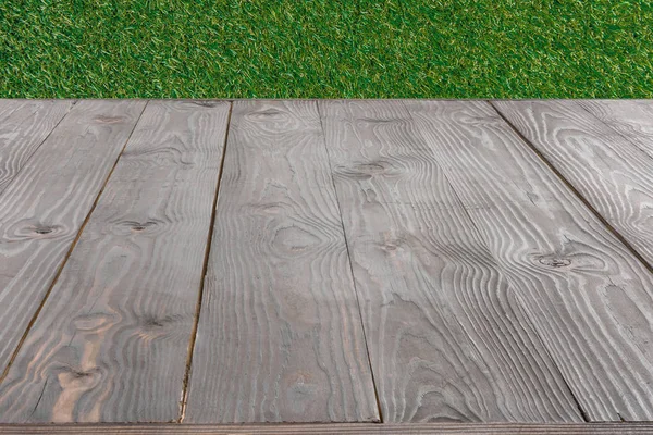 Surface of grey wooden planks with green grass on background — Stock Photo