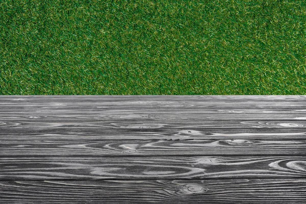 Искушение серого деревянного пола с зеленой травой на фоне — стоковое фото