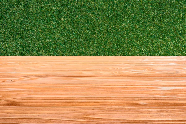 Искушение оранжевого деревянного пола с зеленой травой на фоне — стоковое фото