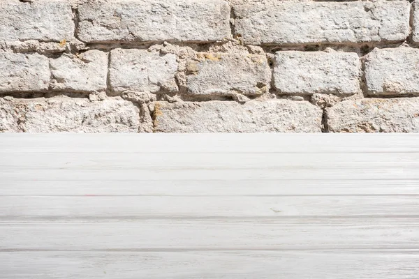 Шаблон белого деревянного пола с кирпичной стеной на фоне — стоковое фото