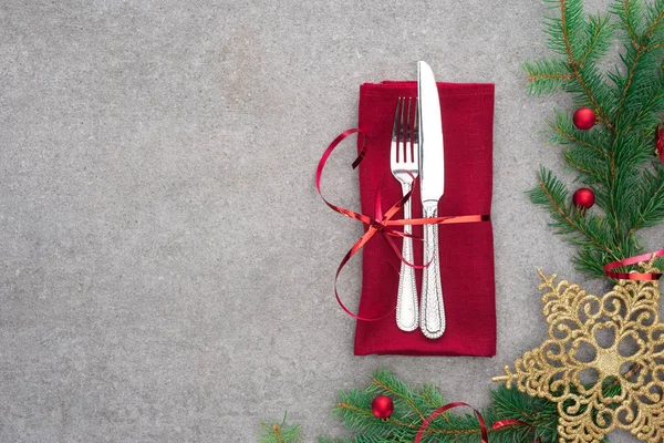 Flat lay com garfo e faca envolto por fita vermelha na mesa com ramo evergreen decorado por bolas de Natal e estrela de Natal de ouro — Fotografia de Stock