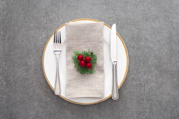 Vista superior del plato servido con tenedor, cuchillo y rama perenne decorada con bolas de Navidad en la superficie gris — Stock Photo