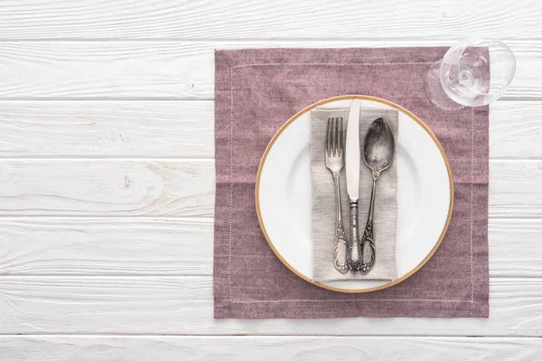 Deitado plano com placa, garfo, faca, colher perto de copo de vinho na mesa servida com toalha de mesa — Fotografia de Stock