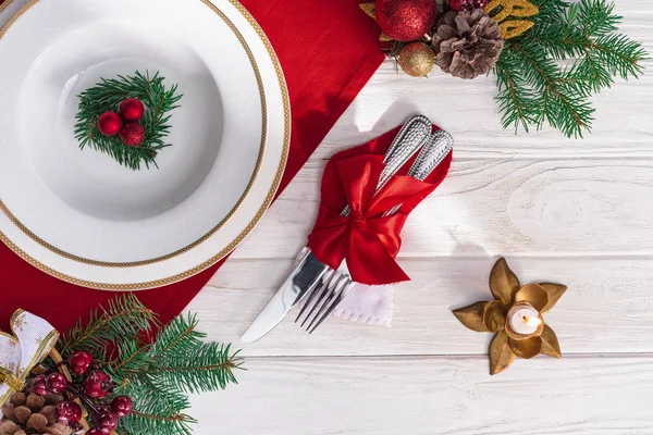 Vista superior de la mesa servida con velas, tenedor y cuchillo, decoración de platos y navidades en mesa de madera - foto de stock