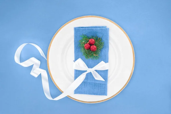 Vista superior de la placa con bolas de Navidad y servilleta envuelta por cinta festiva aislada en azul - foto de stock
