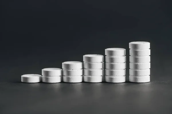 Close up view of arranged stacks of white pills placed in rows on grey — Stock Photo