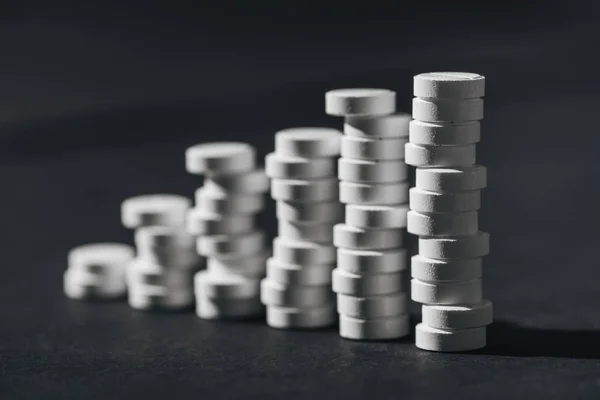 Selective focus of stacks of white pills placed in rows on grey — Stock Photo