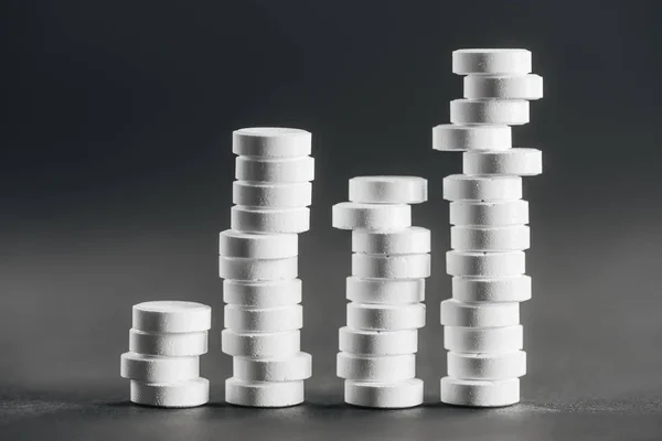 Крупный план стопок белых таблеток, расставленных рядами на сером фоне — стоковое фото