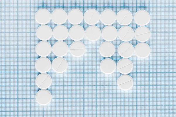 Elevated view of arranged white pills on blue checkered surface — Stock Photo