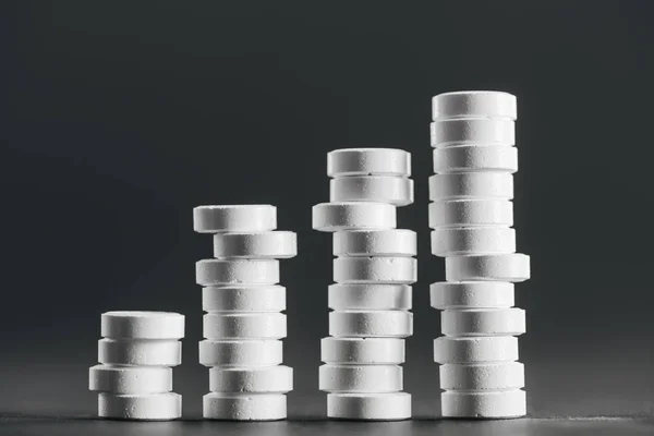 Vue rapprochée des piles disposées de pilules blanches placées en rangées sur le gris — Photo de stock