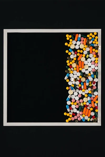 Вид сверху рамы с кучей разноцветных таблеток, изолированных на чёрном фоне — стоковое фото