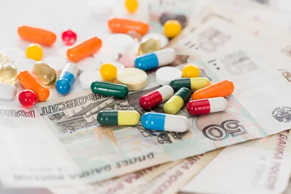 Close up shot of colorful various pills and russian cash money on surface — Stock Photo