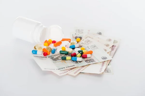 Selective focus of pill bottle, russian cash money and various colorful pills on white surface — Stock Photo