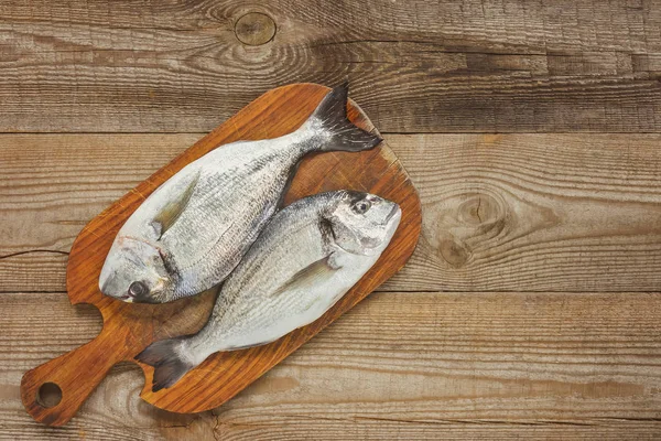 Vista de cima de tábua de madeira com peixe cru na mesa — Fotografia de Stock