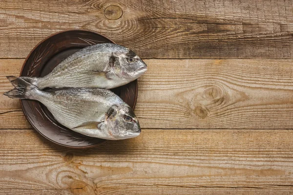 View from above of plate with uncooked fish on wooden table — Stock Photo