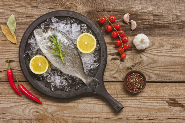 Vista dall'alto del vassoio con pesce crudo vicino agli ingredienti sulla tavola — Foto stock