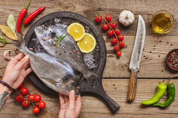 Teilansicht eines tätowierten Mannes, der rohen Fisch auf Tablett legt — Stockfoto