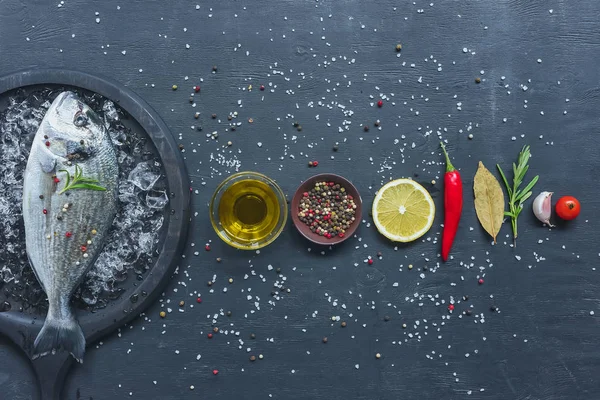 Vista elevata di ingredienti disposti vicino vassoio con pesce crudo sul tavolo nero — Foto stock