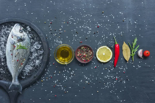 Elevated view of arranged ingredients near tray with uncooked fish on black table — Stock Photo