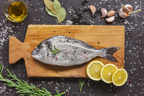 Vista superior de la composición de los alimentos con pescado crudo e ingredientes en tablero de madera - foto de stock